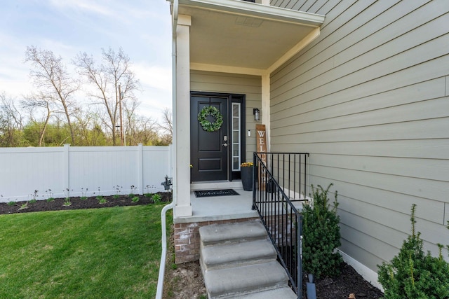 entrance to property featuring fence and a lawn