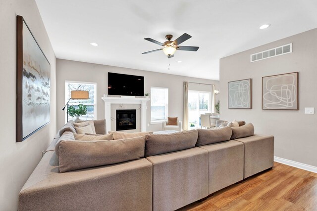 living area featuring a ceiling fan, light wood-style floors, visible vents, and plenty of natural light