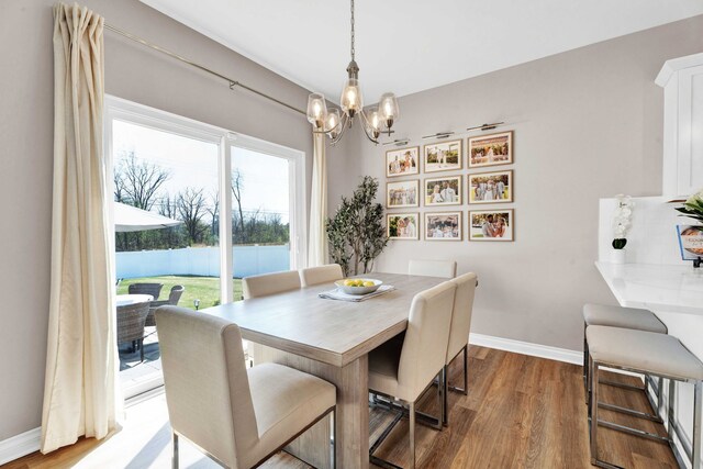 dining space featuring a notable chandelier, baseboards, and wood finished floors
