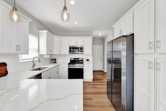 kitchen featuring a sink, appliances with stainless steel finishes, white cabinets, light wood-style floors, and recessed lighting