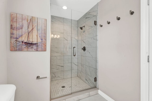 bathroom featuring a stall shower, toilet, baseboards, and marble finish floor