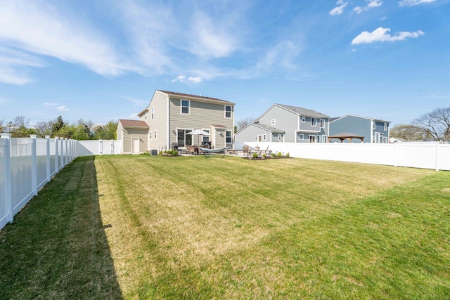 back of property with a fenced backyard and a yard