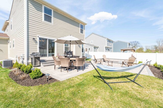 back of house featuring central AC unit, a patio area, a yard, and a fenced backyard