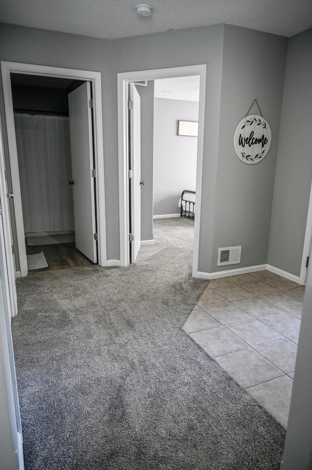 hallway with baseboards, visible vents, and carpet floors
