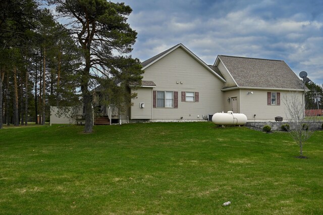 back of property featuring a yard and roof with shingles