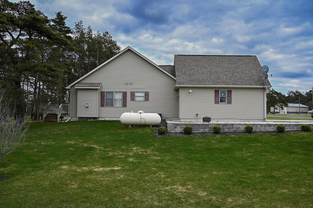 rear view of house featuring a shingled roof and a yard