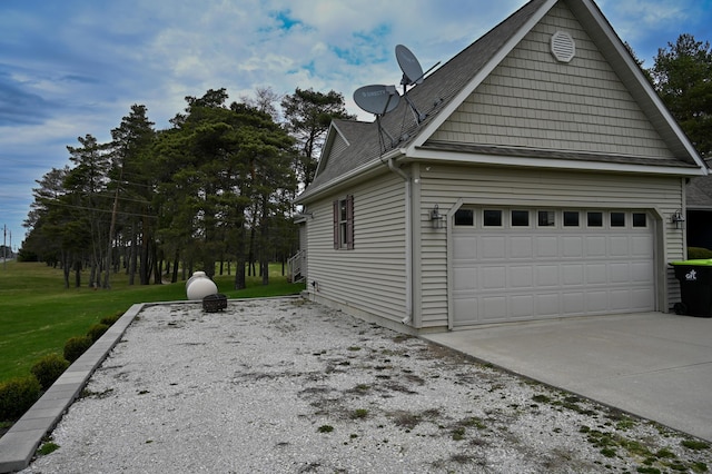view of side of property with driveway, a yard, a shingled roof, and a garage