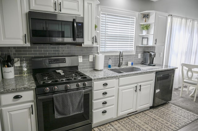 kitchen featuring a sink, tasteful backsplash, light stone counters, white cabinets, and appliances with stainless steel finishes