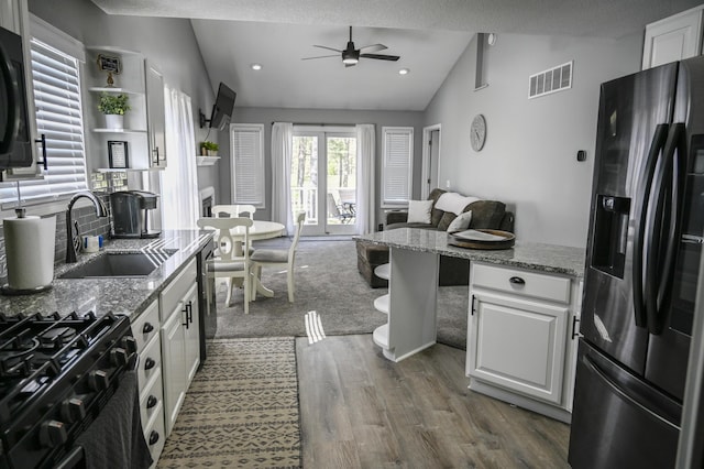 kitchen with stainless steel appliances, vaulted ceiling, ceiling fan, visible vents, and open floor plan