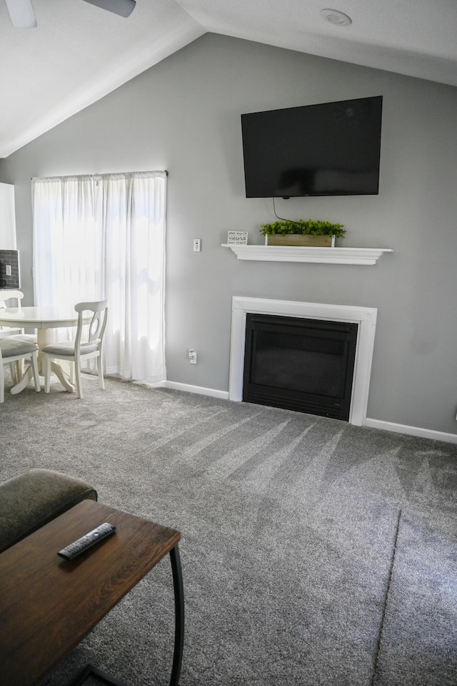 living room with a glass covered fireplace, baseboards, vaulted ceiling, and carpet floors