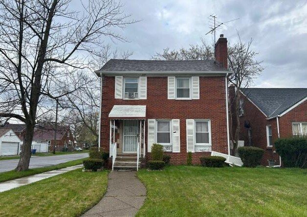 view of front of house with brick siding, a front lawn, and a chimney