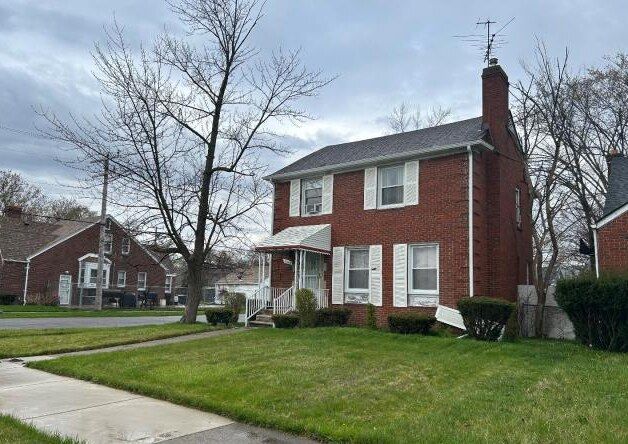view of front of home with brick siding, a chimney, and a front yard