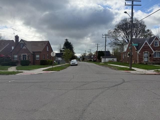 view of street featuring a residential view, sidewalks, traffic signs, and street lighting