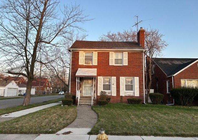 view of front facade featuring a chimney, brick siding, and a front yard