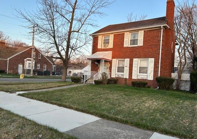 view of front of property with brick siding, a front lawn, and a chimney