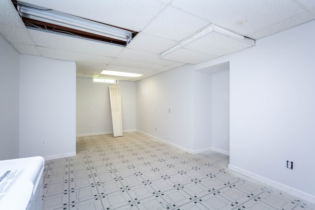 finished below grade area with baseboards, a paneled ceiling, and light floors