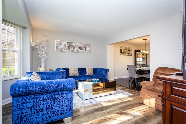living area with baseboards, an inviting chandelier, a healthy amount of sunlight, and wood finished floors