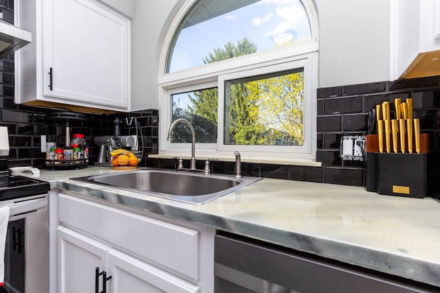 kitchen with a sink, decorative backsplash, white cabinets, and electric stove