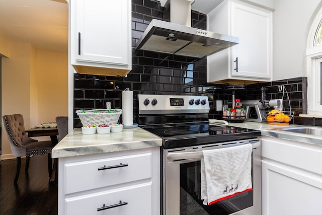 kitchen featuring light countertops, wall chimney exhaust hood, white cabinets, and stainless steel range with electric cooktop