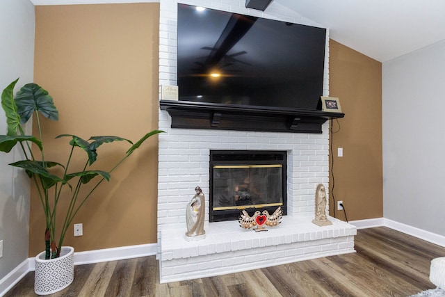 room details featuring baseboards, a brick fireplace, and wood finished floors