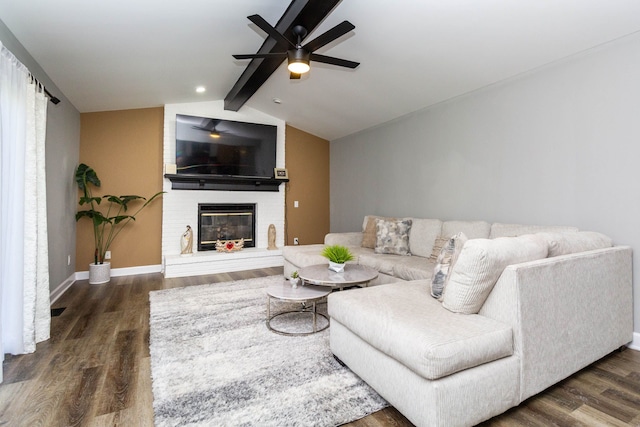 living area with a brick fireplace, ceiling fan, lofted ceiling with beams, and wood finished floors