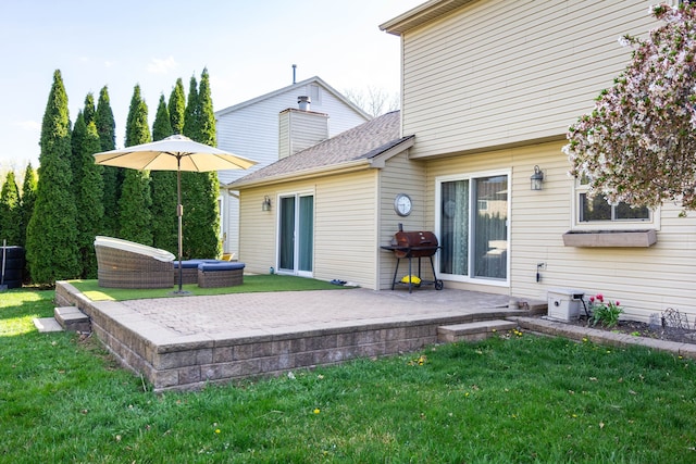 back of property featuring a yard, a patio, and a shingled roof