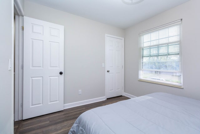 bedroom featuring baseboards and dark wood-style flooring