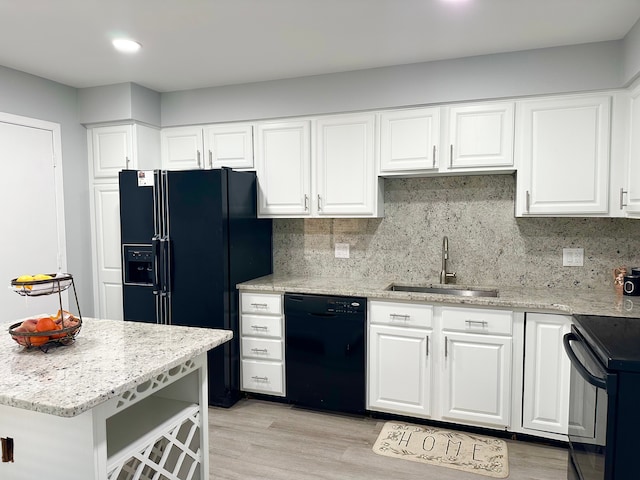 kitchen featuring tasteful backsplash, black appliances, light stone countertops, and a sink