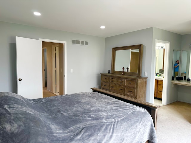 bedroom with visible vents, ensuite bathroom, light colored carpet, and recessed lighting