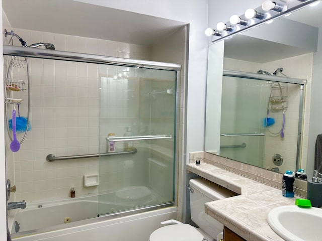 full bathroom featuring toilet, bath / shower combo with glass door, and vanity