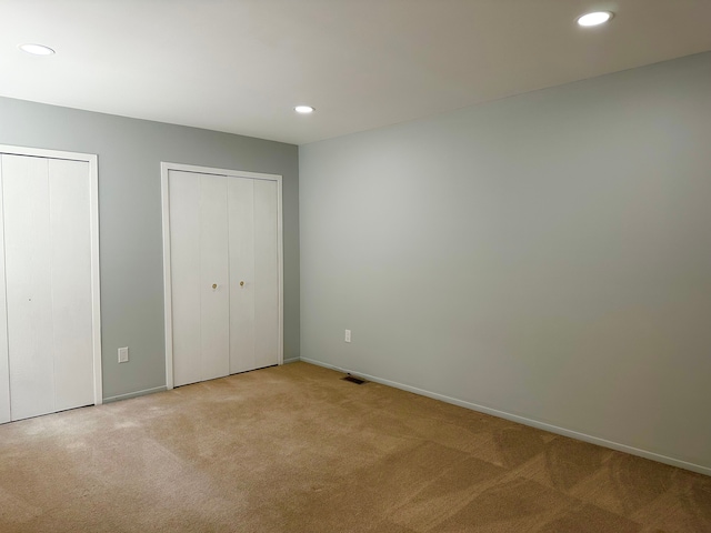 unfurnished bedroom with recessed lighting, two closets, carpet, and baseboards