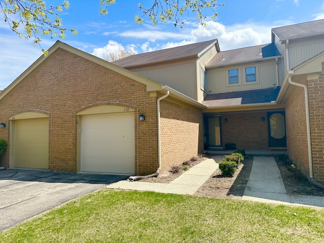 multi unit property with an attached garage, aphalt driveway, and brick siding