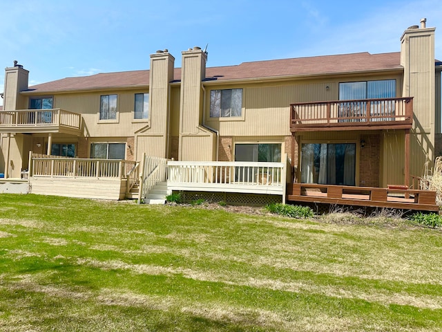 back of property featuring a chimney, brick siding, a balcony, and a lawn