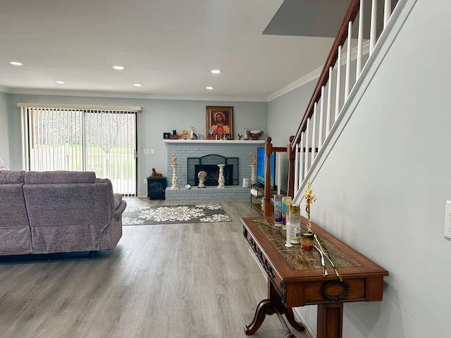 living area featuring recessed lighting, wood finished floors, stairs, a fireplace, and crown molding