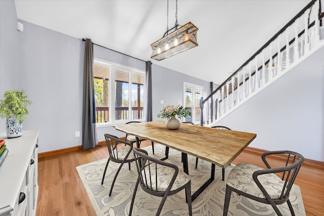 dining space with stairway, baseboards, and light wood finished floors