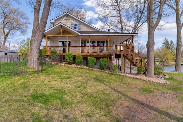 view of front of home with fence, stairs, a water view, and a front lawn