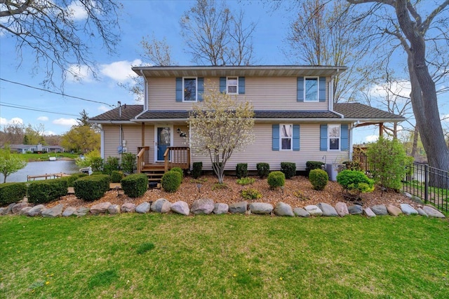 traditional-style home featuring a water view, fence, and a front yard