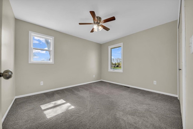 unfurnished room featuring dark colored carpet, baseboards, and a healthy amount of sunlight