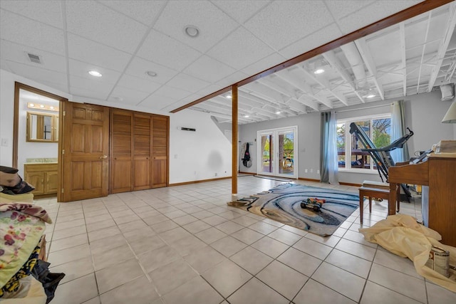 living room featuring light tile patterned flooring, recessed lighting, baseboards, a drop ceiling, and visible vents
