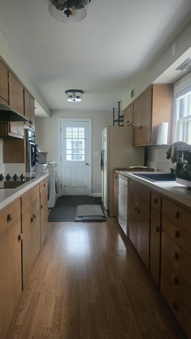 kitchen featuring a sink, washing machine and dryer, visible vents, dishwasher, and wood finished floors