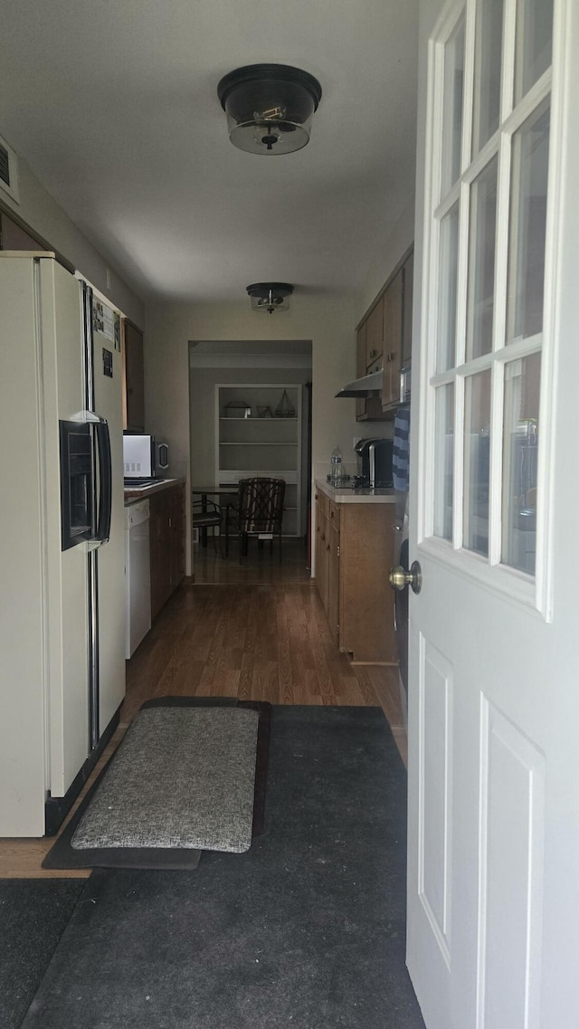 kitchen with visible vents, light countertops, dark wood-style flooring, white appliances, and brown cabinetry