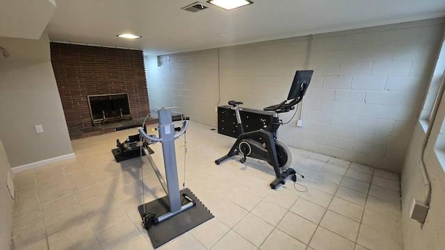 workout room with a brick fireplace, light tile patterned flooring, and visible vents