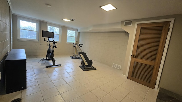 workout area featuring visible vents, light tile patterned floors, and concrete block wall