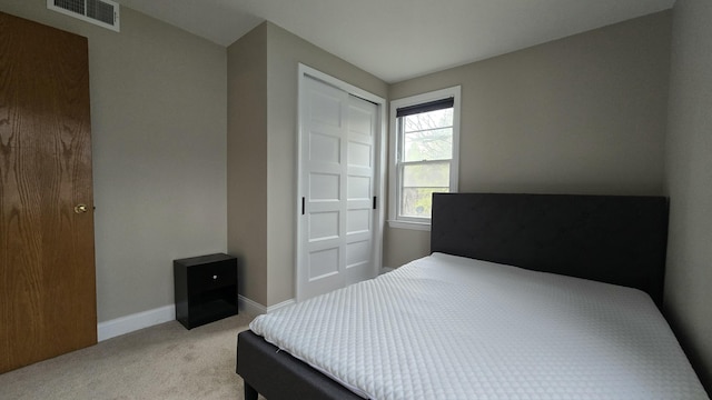bedroom featuring light colored carpet, visible vents, a closet, and baseboards