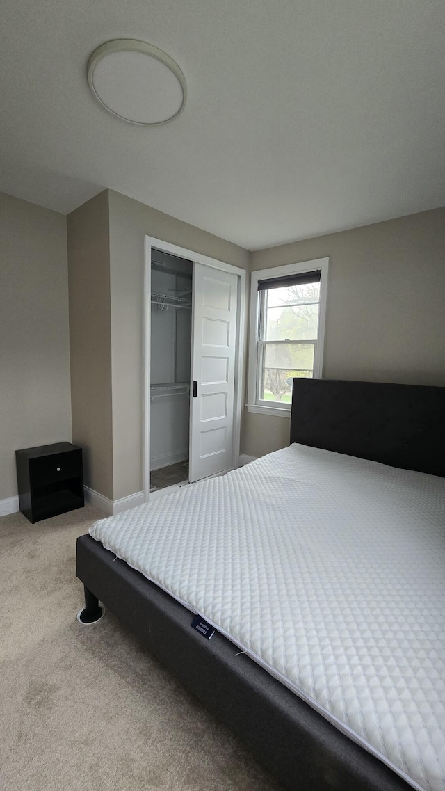 carpeted bedroom featuring baseboards and a closet
