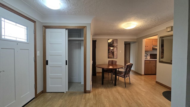 dining area featuring baseboards, a textured ceiling, and light wood finished floors