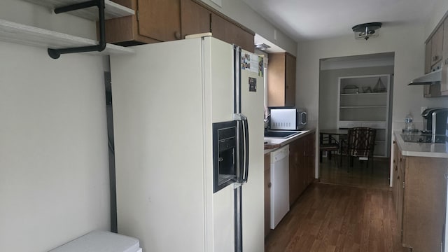 kitchen with dark wood finished floors, white appliances, light countertops, and brown cabinets