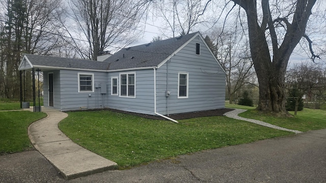 view of home's exterior featuring a chimney, a shingled roof, and a yard