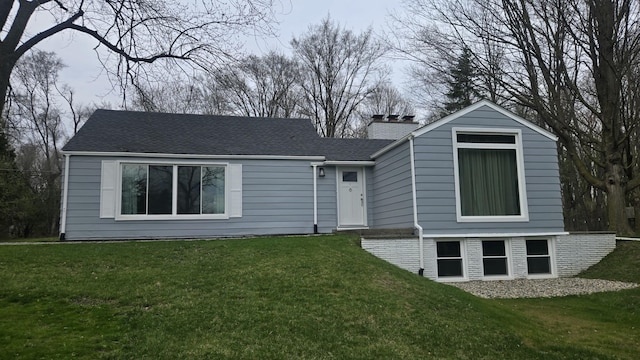 view of front of property featuring roof with shingles, a chimney, and a front yard
