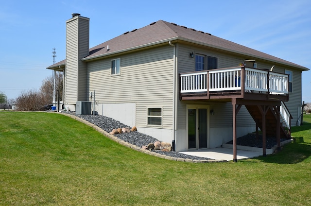 rear view of house with cooling unit, a patio, a deck, a chimney, and a lawn